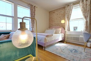 Relax in this inviting bedroom with a plush bed, floor lamp, and comfortable sofa.