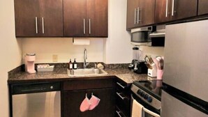 Une cuisine moderne avec des meubles en bois foncé, des appareils électroménagers en acier inoxydable et un luminaire au plafond de couleur rose.