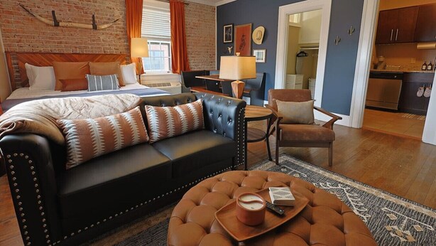 Een moderne slaapkamer met een bakstenen muur, een groot bed, een leren bank en een eethoek.