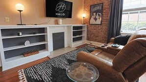 Una sala de estar moderna con chimenea, un televisor empotrado que muestra 'HALO' y un cartel de la película 'CASABLANCA'.