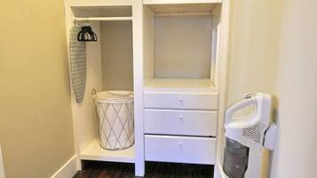 A small, compact kitchen with white cabinetry, a wooden floor, and basic appliances.
