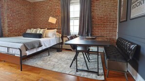 Una habitación pequeña con cama, una mesa de comedor y un banco.