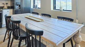 A spacious kitchen with a large dining table, modern appliances, and large windows offering views. - Urban Retreat w/ Downtown Views (Knoxville)