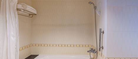A bathroom with a bathtub, shower, and towel rack.