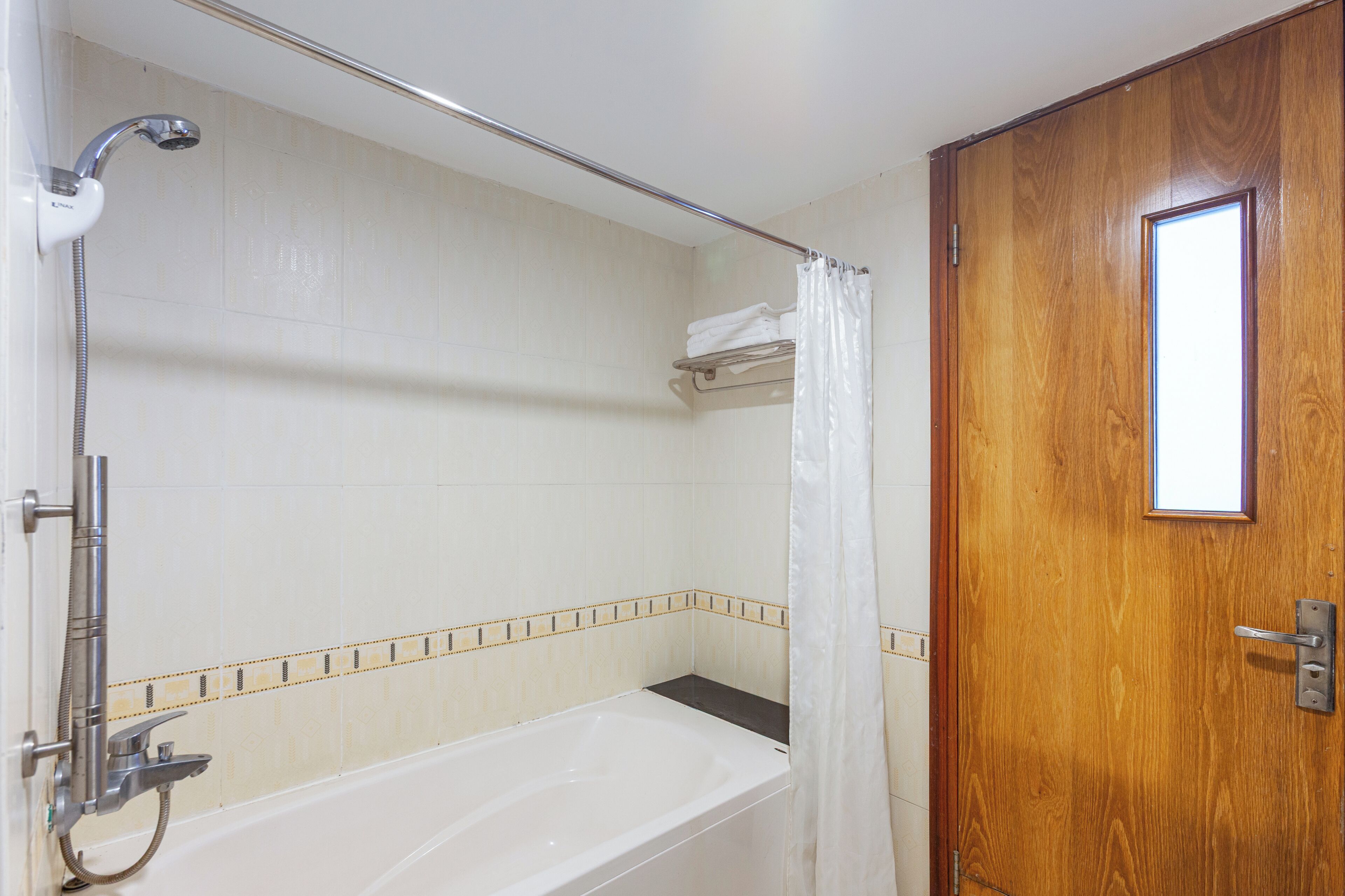Un baño con bañera, ducha y puerta de madera.