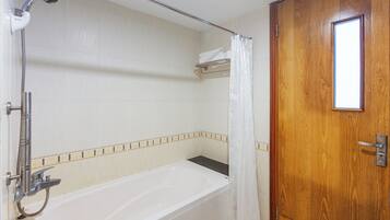 Un baño con bañera, ducha y puerta de madera.