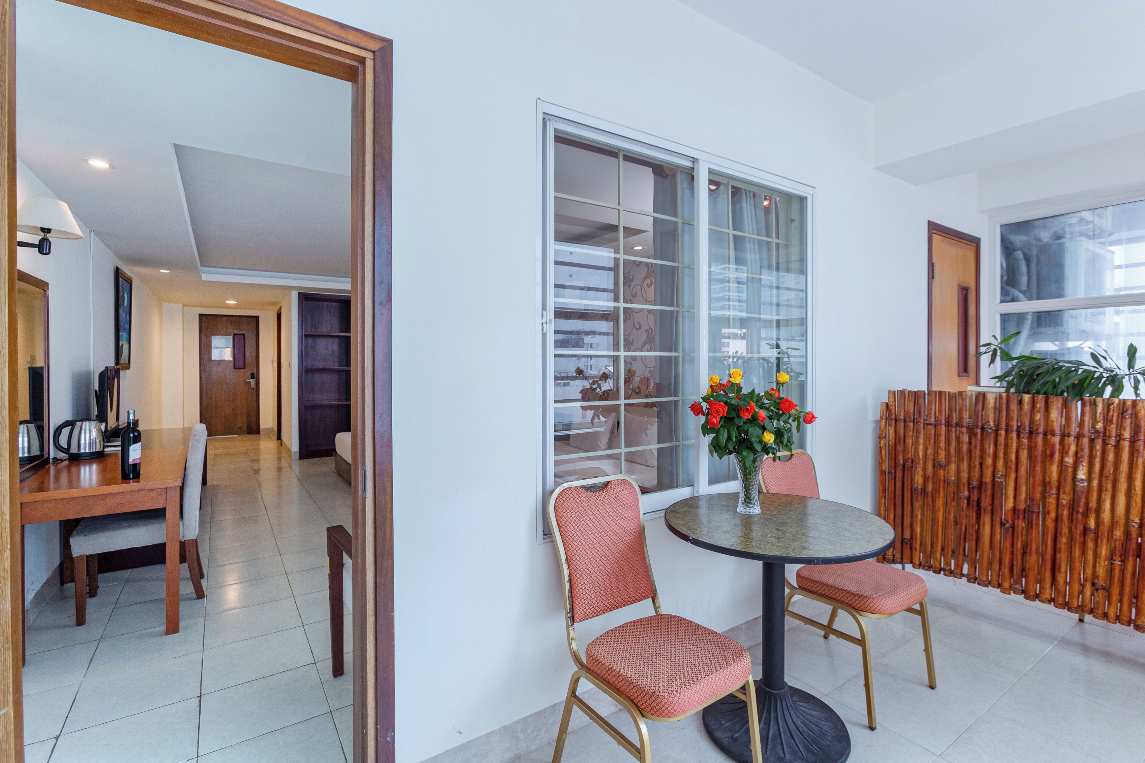 A dining area with a round table, two chairs, and a vase with flowers.