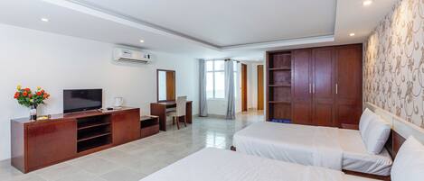 A hotel room with a TV, a desk, a chair, a bed, and a wardrobe.