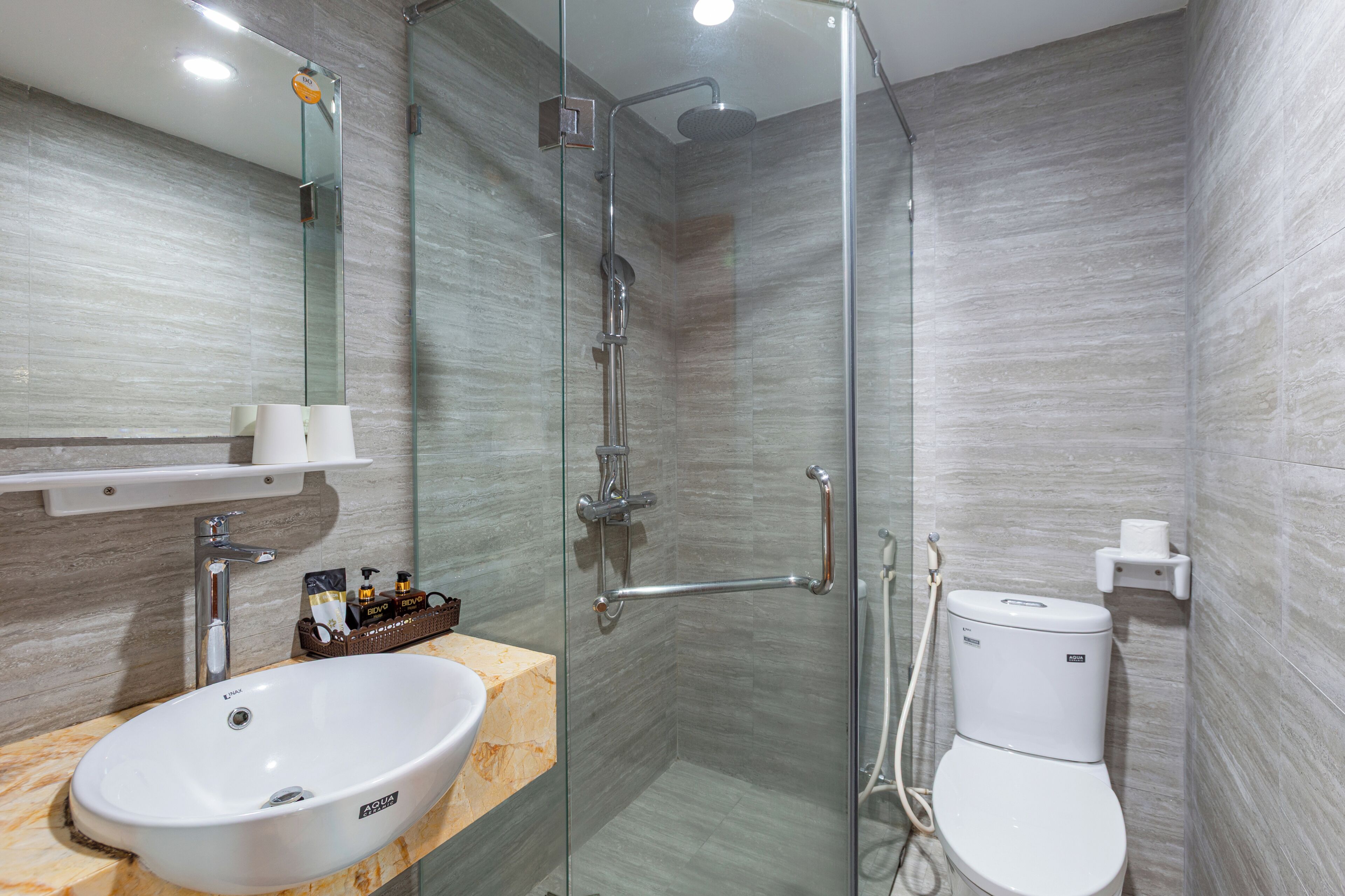 A modern bathroom with a glass-enclosed shower, a white sink, and a toilet.