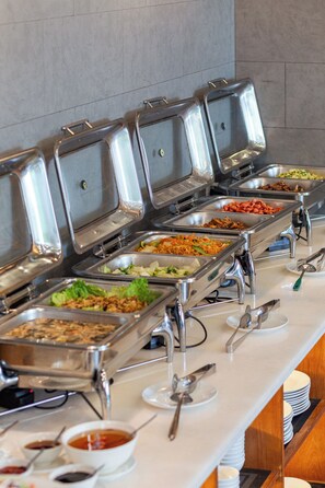 Uma mesa de buffet com diversas opções de comida, incluindo saladas, carnes e macarrão.