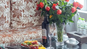 Una mesa de comedor con un sofá estampado con motivos florales, un jarrón con flores y una botella de vino.