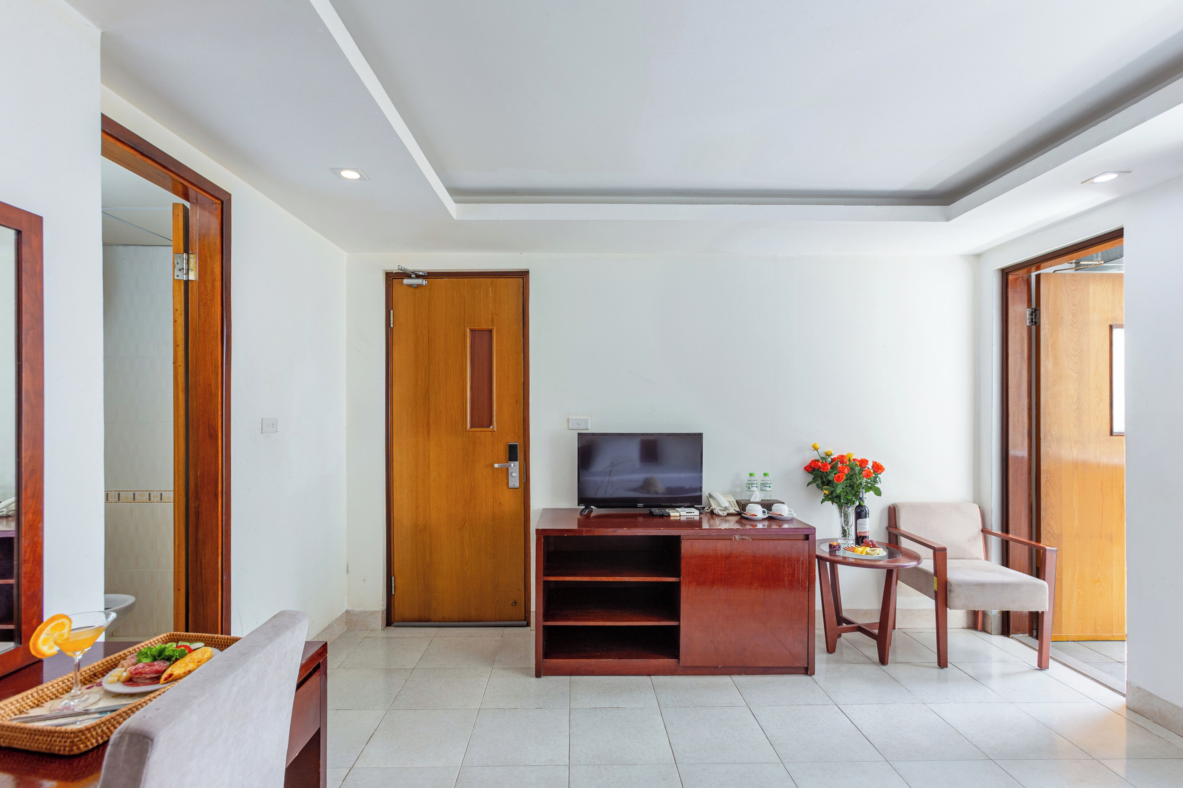 Una sala de estar moderna con televisor de pantalla plana, muebles de madera, un comedor con una bandeja de comida y una puerta.