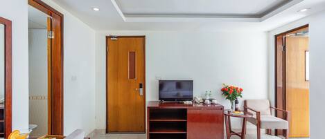 Una sala de estar moderna con televisor de pantalla plana, muebles de madera, un comedor con una bandeja de comida y una puerta.