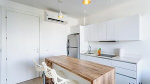 A modern kitchen with white cabinets, a wooden countertop, and a stainless steel refrigerator. - Downtown Condo, Rooftop Pool, Steps to 5th (Playa del Carmen)