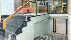 Un hall d’entrée moderne avec un escalier en marbre, des murs en verre et un comptoir d’accueil.