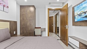 Une chambre à coucher avec un lit, un bureau et un téléviseur fixé au mur.
