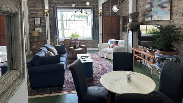 A living room with a sofa set, a coffee table, and a round table. There is a large window with a view outside. - Downtown Mobile near Dauphin, St Louis, Greer's, Saenger, Restaurants - Unit A (Mobile)