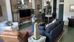 A living room with a TV, leather sofa, blue couch, and a coffee table. - Downtown Mobile near Dauphin, St Louis, Greer's, Saenger, Restaurants - Unit A (Mobile)
