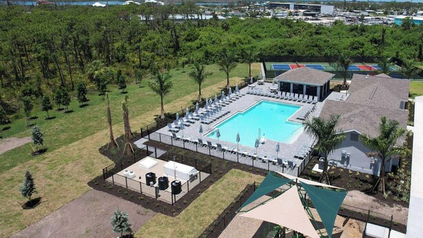 An aerial view of a resort with a swimming pool, lounge chairs, and a tennis court. - Lakefront villa -  pet friendly - near beaches - Hibiscus Haven (Englewood)