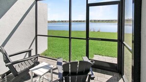 A covered patio with a view of a lake, featuring a table, chairs, and a grill. - Lakefront villa -  pet friendly - near beaches - Hibiscus Haven (Englewood)