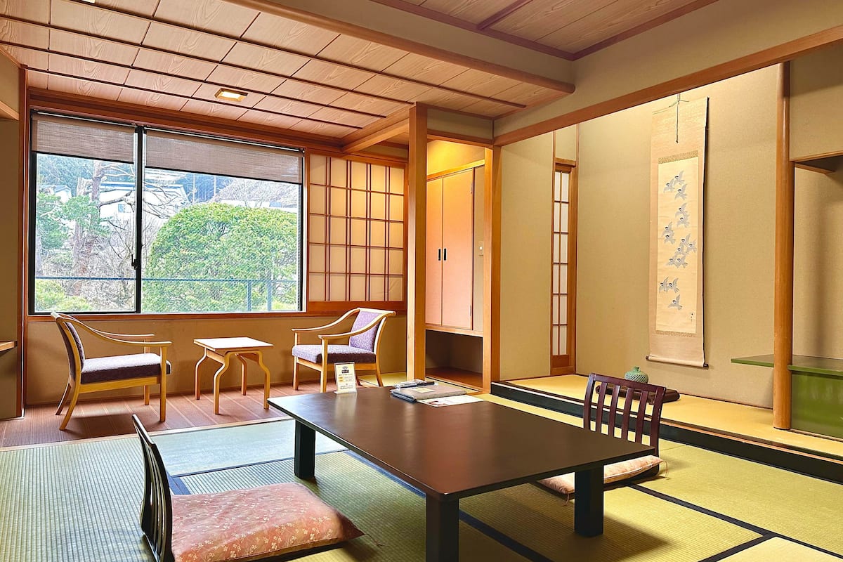 Ett traditionellt japanskt rum med tatamimattor på golvet, ett lågt bord och skjutdörrar.