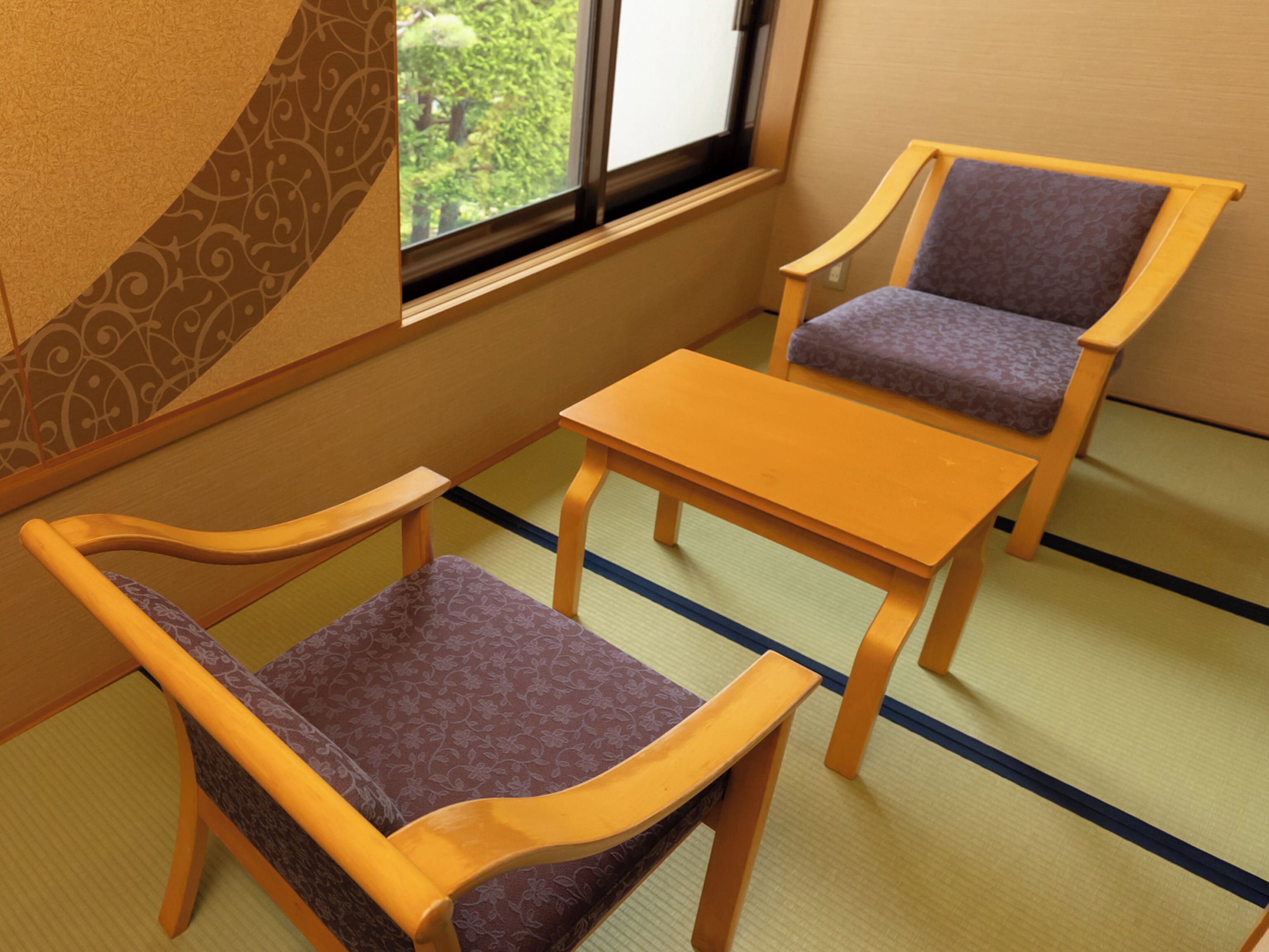 A traditional Japanese room with tatami flooring, two wooden chairs with purple cushions, and a small wooden table.