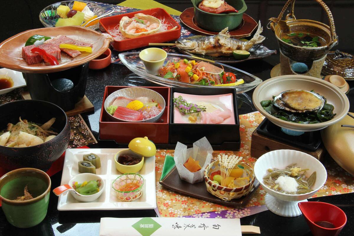 Ett urval av japanska rätter presenterade på ett bord, inklusive sashimi, sushi och andra traditionella maträtter.