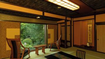Una habitación japonesa tradicional con suelo de tatami, una mesa baja y puertas correderas que dan a un jardín.