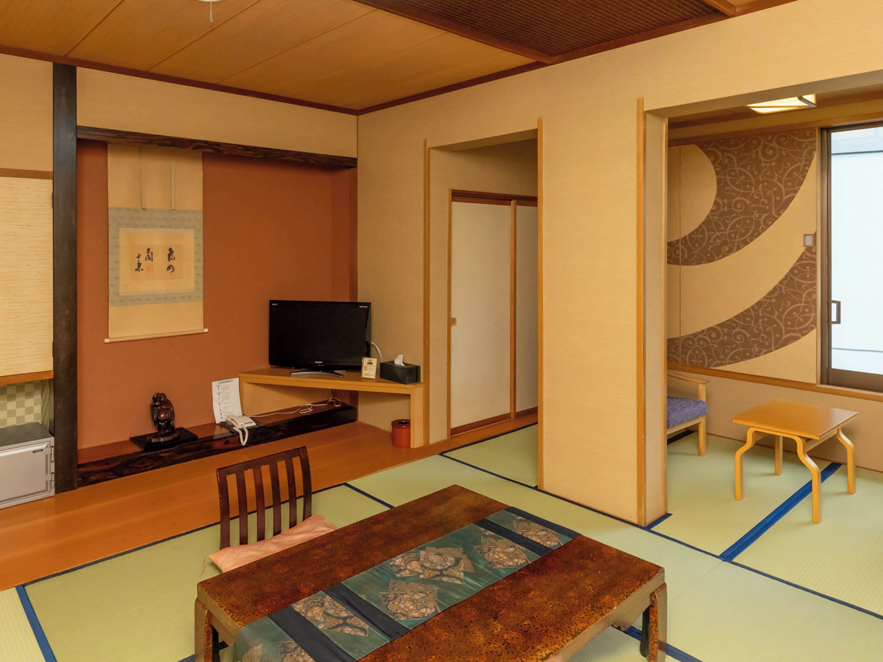 Perinteinen japanilaistyylinen huone, jossa on tatamimatto, matala pöytä, televisio ja liukuovi.