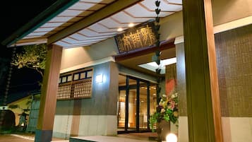 Traditional Japanese-style building with a wooden gate and steps leading to the entrance.