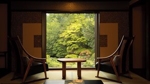 Une pièce de style japonais traditionnel, avec un sol recouvert de tatamis, une petite table en bois et deux chaises en bois.