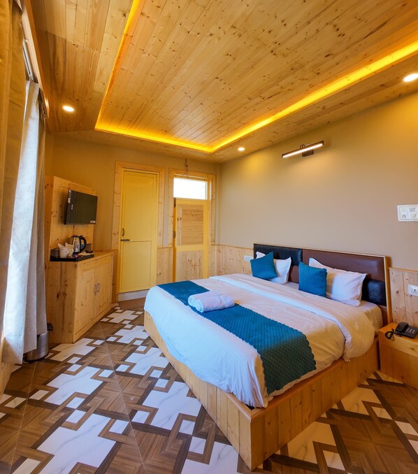 A wooden-paneled bedroom with a bed, a TV, and a window.