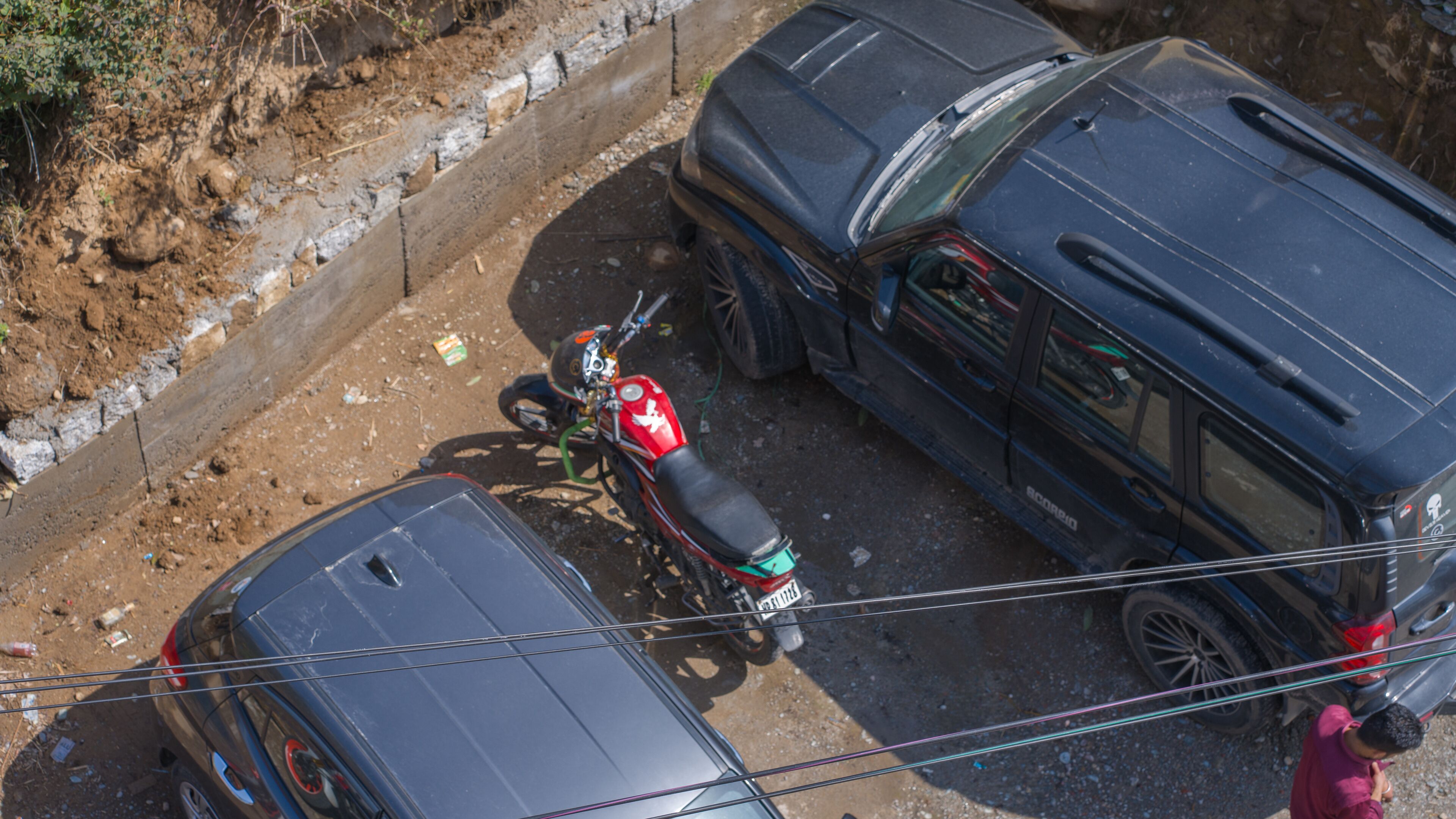 A parking area with a motorcycle, a car, and a large vehicle.