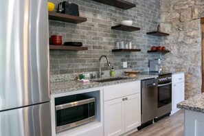 Une cuisine moderne dotée de plans de travail en granit, d’appareils électroménagers en acier inoxydable et d’étagères intégrées.