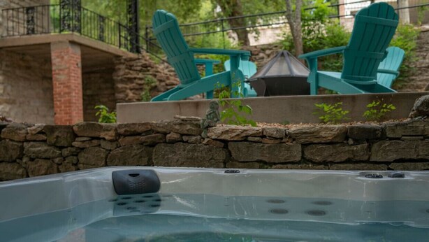 Un jacuzzi con una pared de piedra y una terraza de madera.