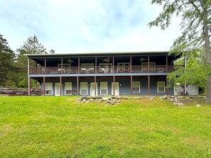 A two-story building with a balcony, multiple windows, and a grassy yard.