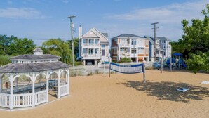 A beach with a gazebo, a sign reading "COSTER HARBOR", and a row of multi-story buildings in the background. - Waterfront Home with Private Dock, Community Beach (Annapolis)