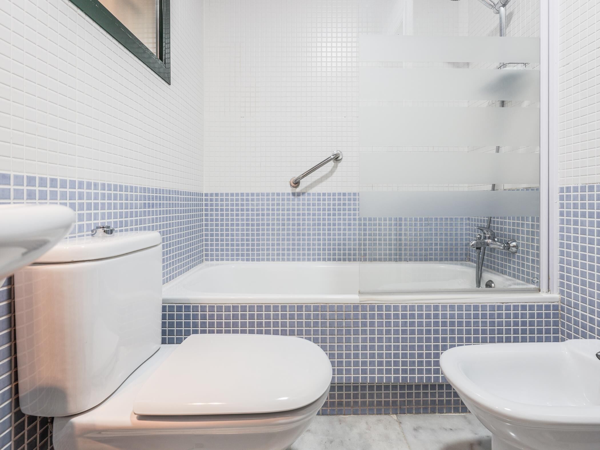 A bathroom with a toilet, bidet, and bathtub.