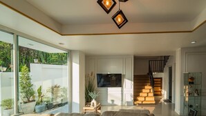 A modern living room with a sofa, a TV, and a staircase leading to another level. - The Scoop Sea view Kamala 10km to Patong (Kamala)