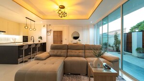 A modern living room with a large sectional sofa, a dining area with bar stools, and a kitchen with a built-in island. - The Scoop Sea view Kamala 10km to Patong (Kamala)