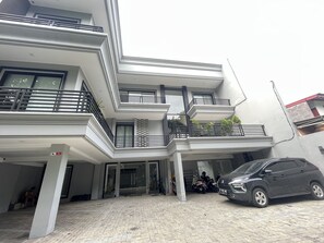 A multi-story residential building with balconies, a covered parking area, and a car parked in the driveway. - OYO 93721 RuPA Near LRT Velodrome 2 Rawamangun (Jakarta)