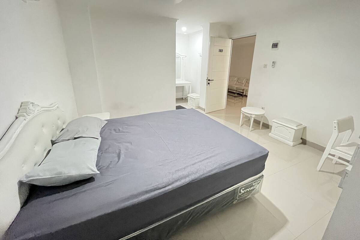 Un dormitorio con cama, mesitas de noche, una silla y un armario.