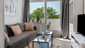 Una sala de estar moderna con un sofá, una mesa de centro de vidrio y un televisor.