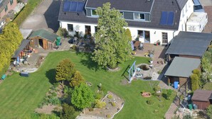 A residential property with a large lawn, a pond, solar panels, and a variety of outdoor furniture. - Apartment "Zur Eule - Uhu" with Shared Garden & Wi-Fi (Satow OT Clausdorf)