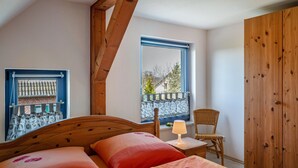 A bedroom with a wooden headboard, a window with a view, a chair, and a wardrobe. - Apartment "Zur Eule - Uhu" with Shared Garden & Wi-Fi (Satow OT Clausdorf)