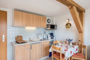 A compact kitchen with wooden cabinets, a microwave, a sink, and a dining area with a table set for two.