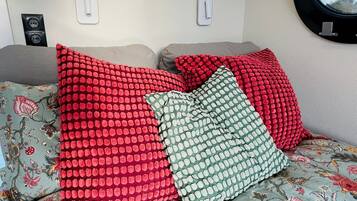 A bed with floral bedding and red and green patterned pillows.