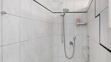 Eine moderne Dusche mit Duschbrause, Wandarmatur und Seifenspender.