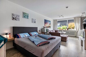Een moderne slaapkamer met een groot bed, een bureau, een stoel en uitzicht op de natuur.