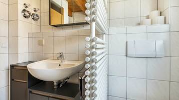 Une salle de bain avec un lavabo blanc, un miroir, un porte-serviettes et des toilettes.